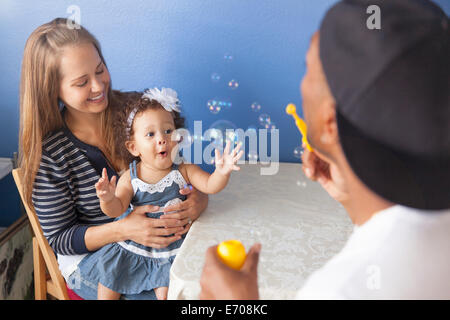 Mère et père jouant avec sa jeune fille, père blowing bubbles Banque D'Images
