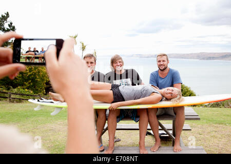 Young woman photographing with smartphone amis surfeur Banque D'Images