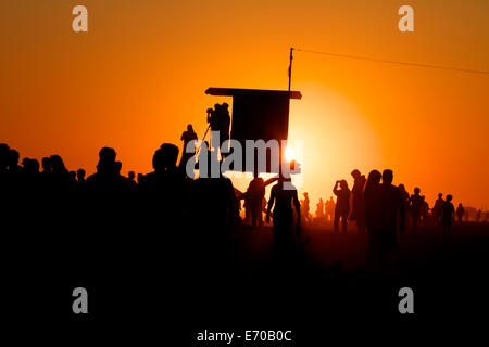 Lifeguard tower avec une foule de gens silhouetté contre un coucher du soleil doré à Newport Beach en Californie Banque D'Images