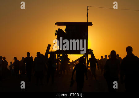 Lifeguard tower avec une foule de gens silhouetté contre un coucher du soleil doré à Newport Beach en Californie Banque D'Images