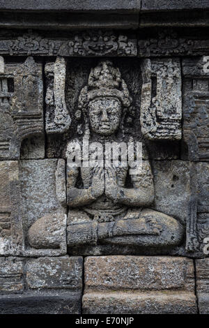 Borobudur, à Java, en Indonésie. La sculpture sur pierre, assis en position du lotus, les mains ensemble. Banque D'Images