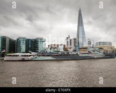 Le HMS Belfast bateau musée vue de la Tamise sur un jour d'été couvert avec le tesson et plus le développement de la rivière derrière Banque D'Images