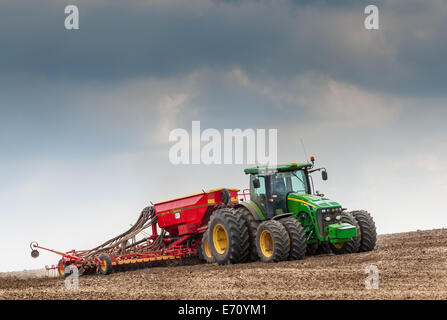 Tracteur agricole avec une perceuse à l'arrière, perçage ou l'ensemencement, l'herbe sur un champ qui a été préparé ou labourée (labourées) Banque D'Images