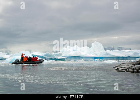 Les gens en zodiac bateaux rib passant d'icebergs et de plaques de glace sur l'eau calme autour de petites îles de l'Antarctique. Banque D'Images