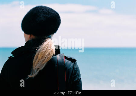 Vue arrière d'une femme dans un chapeau noir qui donnait sur la mer. Banque D'Images