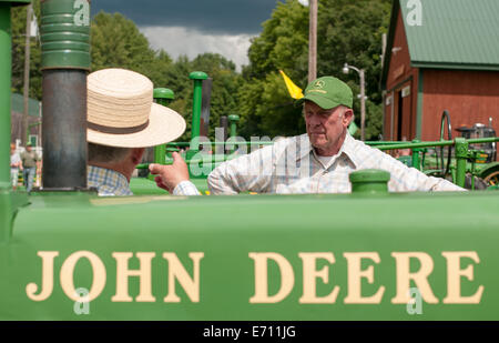 Deux hommes en chapeaux de discuter à un tracteur John Deere Expo de New Hampshire. Banque D'Images