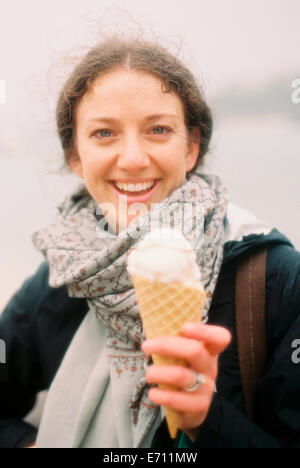 Une femme tenant une glace dans un cône et rire. Banque D'Images