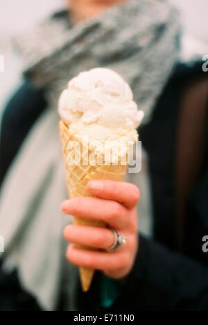 Une femme tenant une glace dans un cône et rire. Banque D'Images