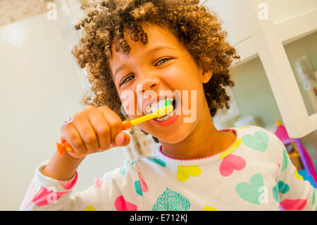 Portrait of smiling girl se brosser les dents dans la salle de bains Banque D'Images