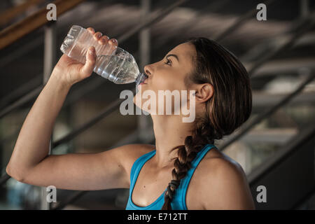 Jeune femme à boire l'eau de bouteille Banque D'Images