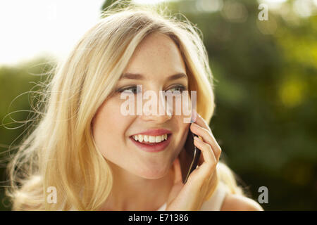 Young woman chatting on smartphone in park Banque D'Images