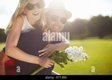 Jeune femme avec des fleurs se greffer de copain dans park Banque D'Images