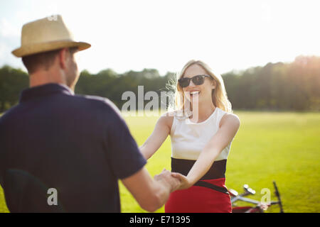 Couple holding hands and swirling autour dans park Banque D'Images