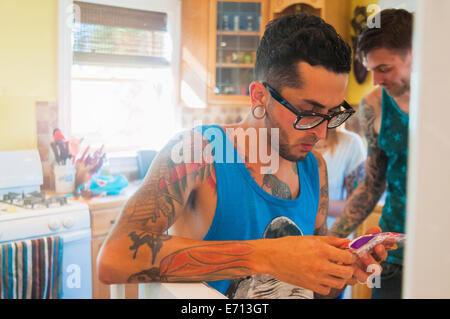 Mid adult man texting on smartphone in kitchen Banque D'Images