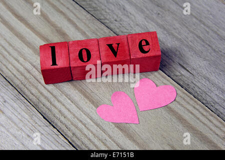 Mot d'amour sur les cubes en bois et deux coeur de papier sur fond de bois Banque D'Images