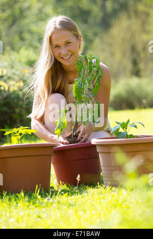 Portrait of smiling teenage girl rempotage plante dans le jardin Banque D'Images