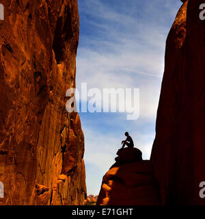 Silhouette de femme assise sur pierre dans rock canyon dans Arches National Park Banque D'Images