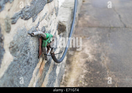 Un injecteur et un flexible de pompe à essence à panne unique fixés à un mur d'une station-service à longue durée Banque D'Images