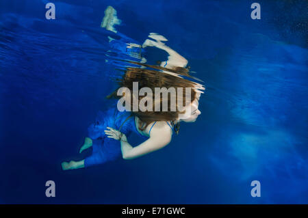 Une jeune femme avec de grands cheveux de poser dans un pool underwater Banque D'Images