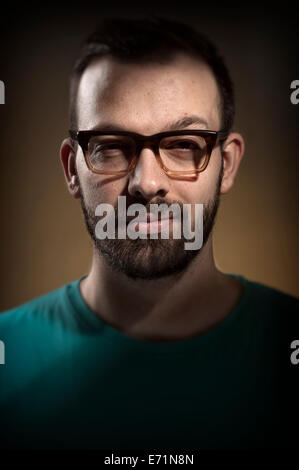 Jeune mec lunettes retro hipster. Lumière dramatique Banque D'Images