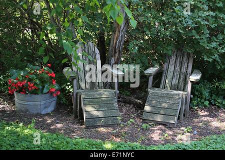 Deux vieilles chaises en bois à l'ombre à côté d'un pot de fleurs. Banque D'Images