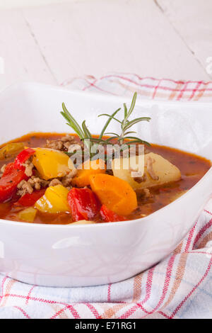 Ragoût copieux avec des légumes dans un bol avec cuillère sur torchon à carreaux Banque D'Images