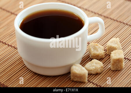 Tasse de café et de sucre de canne brun sur bambou serviette. Profondeur de champ. L'accent sur le sucre de canne. Focus sélectif. Libre. Banque D'Images