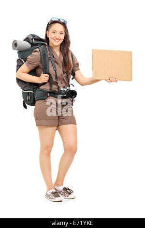 Full Length portrait of a female hiker holding a blank sign carton isolé sur fond blanc Banque D'Images