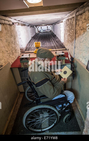 Un fauteuil roulant à l'aide de hauts homme handicapé vérifier ses scores sur la cible à un club de tir éventail UK Banque D'Images