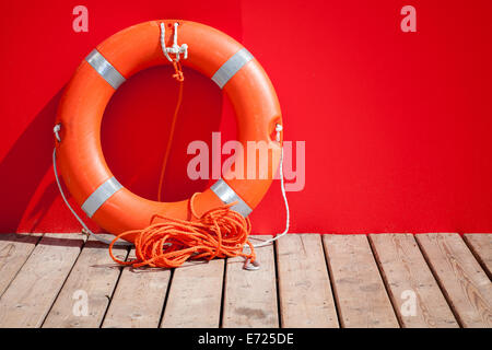 Bouée se dresse sur un plancher en bois à proximité de mur rouge lifeguard station Banque D'Images