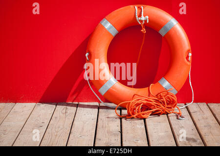 Bouée se dresse sur un plancher en bois à proximité de mur rouge lifeguard station Banque D'Images