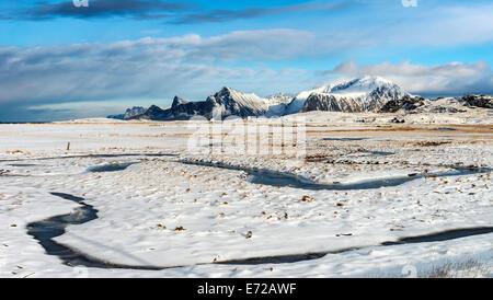 Un ruisseau gelé serpentant à travers la neige à Fredvang sur les îles Lofoten Banque D'Images