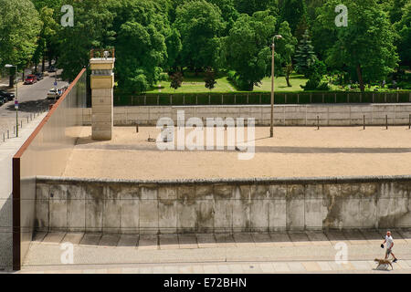 Allemagne, Berlin, Gedenkstatte Berliner Mauer, également connu sous le nom de Mémorial du Mur de Berlin Exposition au mémorial de la Bernauer Strasse contient le dernier morceau de mur de Berlin qui a conservé le motif de la bande frontalière affiche derrière elle. Banque D'Images