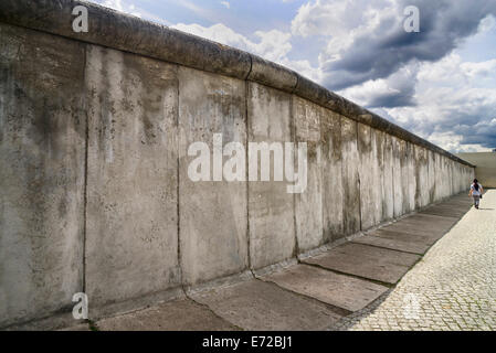 Allemagne, Berlin, Gedenkstatte Berliner Mauer, également connu sous le nom de Mémorial du Mur de Berlin Exposition au mémorial de la Bernauer Strasse contient le dernier morceau de mur de Berlin qui a conservé le motif de la bande frontalière affiche derrière elle. Banque D'Images