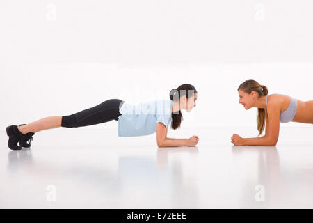 Deux happy young woman doing push-ups in gym Banque D'Images