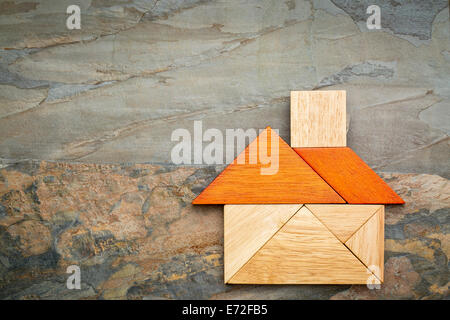 Résumé photo d'une maison construite à partir de sept pièces en bois tangram contre rock fond ardoise Banque D'Images