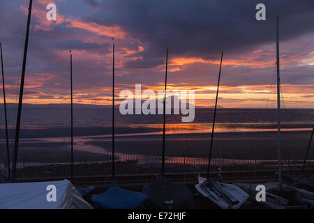 Course de canots alignés sur la promenade à Prestwick tandis que le soleil se couche derrière l'île d'Arran. Banque D'Images