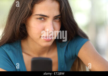 Portrait d'une fille de l'adolescence avec un smart phone looking at camera Banque D'Images