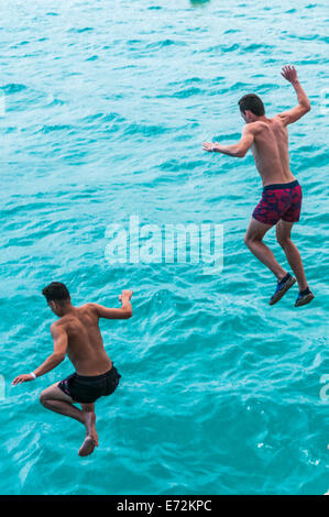 Deux jeunes hommes sautant d'une falaise dans la mer près de Calas de Mallorca Banque D'Images