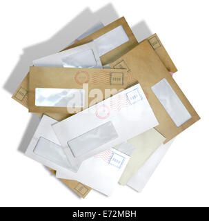 Une pile d'enveloppes ordinaires dispersés avec des timbres et une fenêtre claire sur un fond blanc Banque D'Images