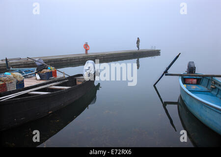 Femme seule sur le quai du petit port de pêche d'Agios Achilleios islet, Mikri Prespa Lake, Florina, Macédoine, Grèce. Banque D'Images