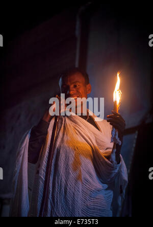 Prêtre tenant une bougie à l'intérieur d'une église de roche, Lalibela, Éthiopie Banque D'Images