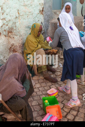 Les enfants en donnant de la nourriture à un pauvre mendiant dans la rue, Harar, en Ethiopie Banque D'Images