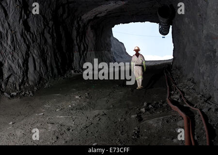 Mineur africain descendant la pente pour vérifier l'accès du tunnel de service à la nouvelle mine souterraine de platine - depuis le portail d'entrée du puits de rampe. Afrique du Sud Banque D'Images