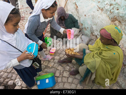 Les enfants en donnant de la nourriture à un pauvre mendiant dans la rue, Harar, en Ethiopie Banque D'Images