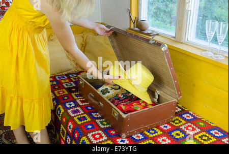 Femme avec Robe jaune paille mettre chapeau dans le vieux cuir valise Banque D'Images