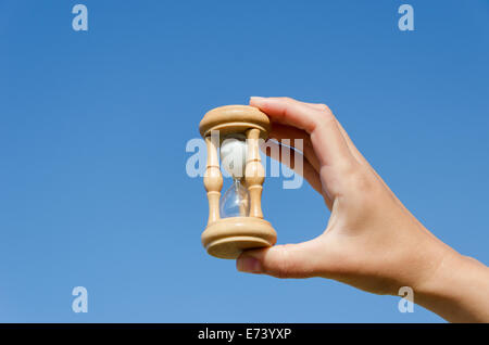 Main courante en bois miniature vintage retro hourglass sur fond de ciel bleu Banque D'Images