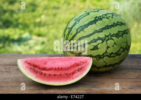 Une tranche de melon et son ensemble l'un sur une table en bois Banque D'Images