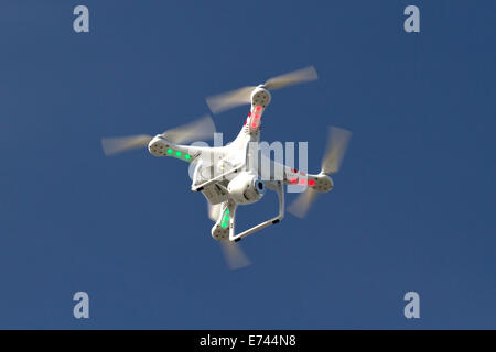 Petit hélicoptère sans pilote avec un appareil photo flottant dans le ciel bleu Banque D'Images