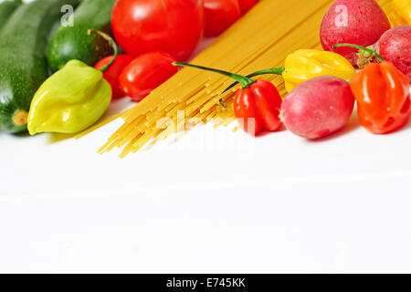 Les pâtes Spaghetti aux légumes crus sur un fond blanc Banque D'Images